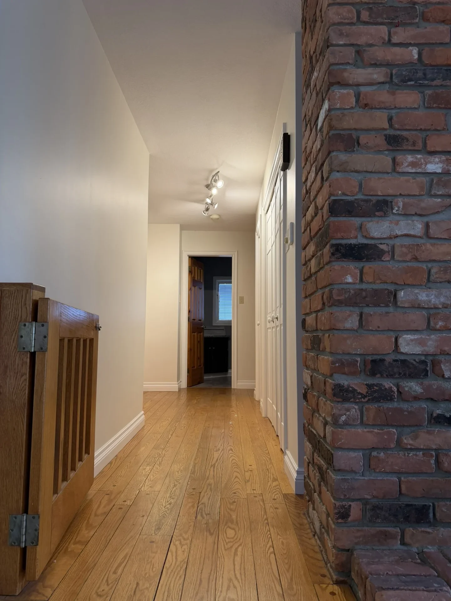 Upstairs hallway framed by an exposed red brick chimney
