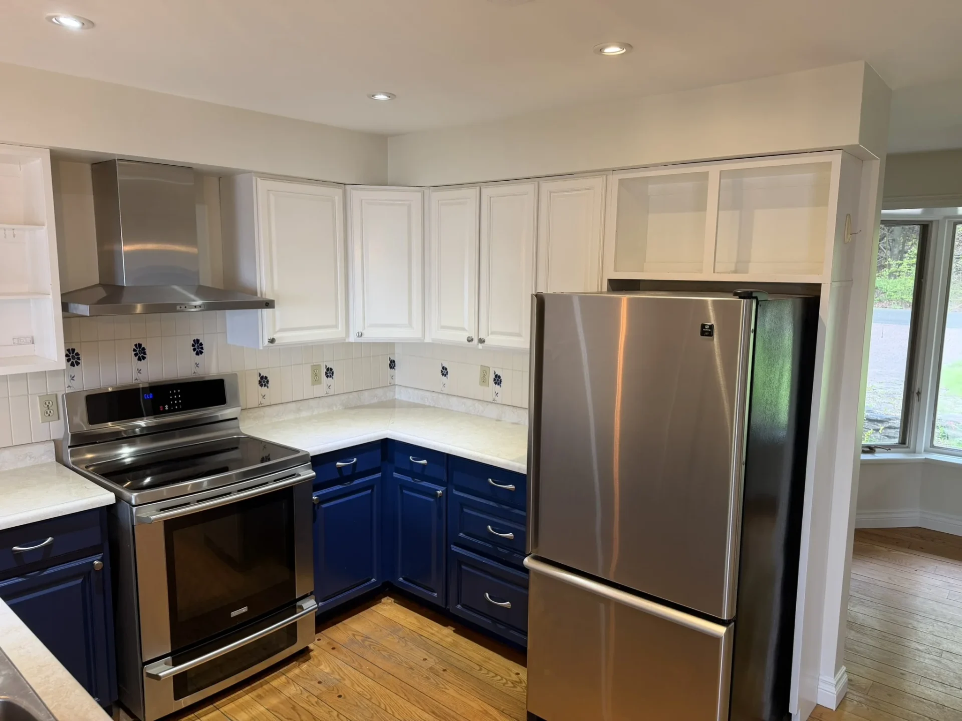 Kitchen with navy cabinetry, stainless appliances, and decorative tile backsplash