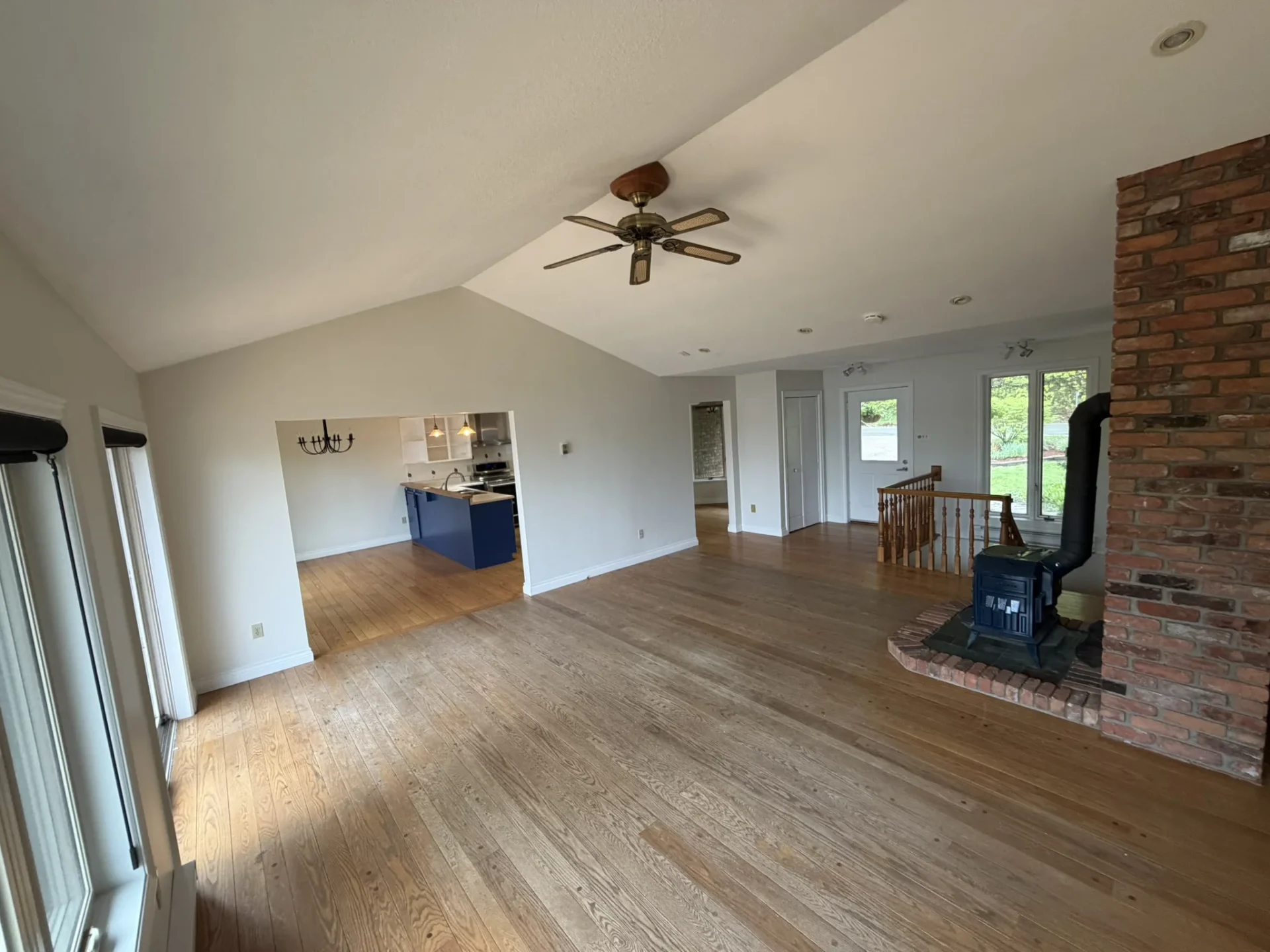 Open-concept living room with vaulted ceilings, wood stove, and brick chimney